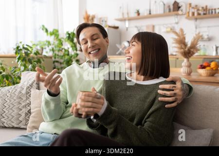 In einem ruhigen Wohnraum teilt ein fröhliches Paar Lachen und Wärme und umschließt sich glücklich. Stockfoto