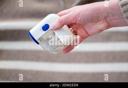 Elektrischer Textilrasierer in weiblicher Hand zum Entfernen von Fusseln aus dem Pullover Stockfoto
