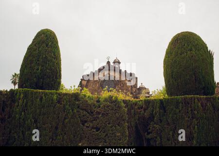 Ruhiger Blick auf den Garten. Ruhige Klostergartenszene. Friedlicher Innenhof mit traditioneller Architektur. Ruhige Klosteranlage mit symmetrischer Atmosphäre Stockfoto