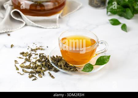 Tasse gesunder grüner Tee mit Teeblättern. Stockfoto
