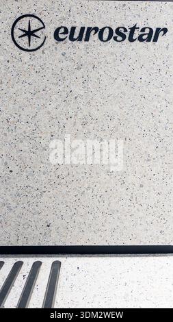 Nahaufnahme des Eurostar-Logos in kräftigem schwarzem Schriftzug mit ineinander greifendem Sternsymbol auf der strukturierten weißen Terrazzo-Kieselwand, die an den Hochgeschwindigkeitszug trave erinnert Stockfoto