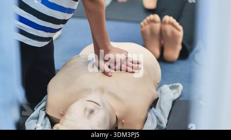 Hände, die Thoraxkompressionen an einer medizinischen Trainingspuppe durchführen, um lebensrettende Fähigkeiten zu gewährleisten Stockfoto