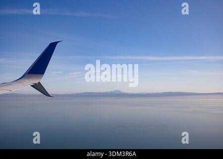 Blick auf ein Winglet der United Airlines Boeing 737, das über einem riesigen blauen Himmel und Ozean schwingt, während des Fluges aus einem Passagierfenster aufgenommen. Stockfoto