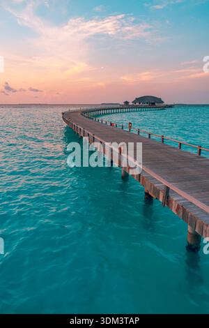 Strahlender maledivischer Ozean Sonnenuntergang mit tropischem Pier und ruhigen Wellen ruhiger Inselparadies Himmel entspannender Sommer Seascape Reise Hintergrund Stockfoto