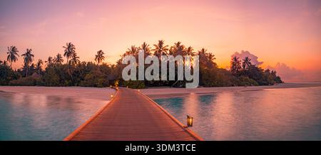 Strahlender Sonnenuntergang auf den Malediven über dem Pier mit tropischem Ozean und Palmen ruhiges Inselparadies glühende Sommerlandschaft mit romantischem Reisehintergrund Stockfoto