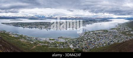Ultrabreiter Panoramablick vom Storsteinen aus zeigt die gesamte Stadt Tromsø, die sich entlang des Fjords ausbreitet, eingerahmt von fernen schneebedeckten Bergen Stockfoto