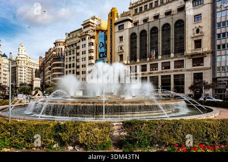 Der runde Brunnen auf der Plaza del Ayuntamiento sprüht Wasser vor dem Hintergrund ikonischer Art déco-Gebäude wie dem Rialto Theater. Stockfoto
