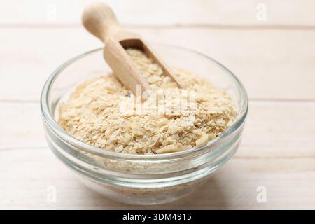 Trockene Hefeflocken in Schüssel und Löffel auf Holztisch, Großaufnahme Stockfoto