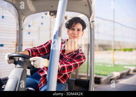 Chilenische Frau Gabelstaplerfahrerin, die das Fahrzeug im Gewächshaus fährt Stockfoto