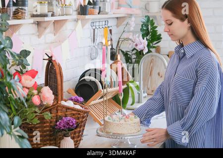 Frohe Ostern. Kaukasische Frau steht an der Küchentische zum Osteressen und hält einen Kuchen || Model veröffentlicht Stockfoto