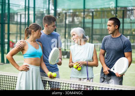 Glückliche Spieler mit Schlägern für Padel, die auf dem Tennisplatz im Freien reden Stockfoto