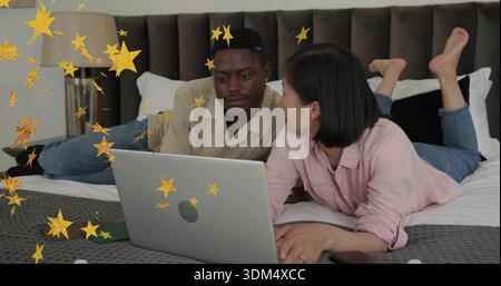 Paare, die auf dem Bett liegen, mit cremefarbenen, rosa Oberteilen, Laptop in der Nähe von grünem Telefon, goldenen Sternen Stockfoto