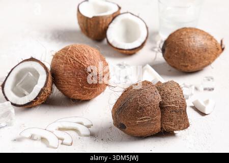 Frische Kokosnüsse mit Eiswürfeln und einem Glas Wasser auf weißem Hintergrund Stockfoto
