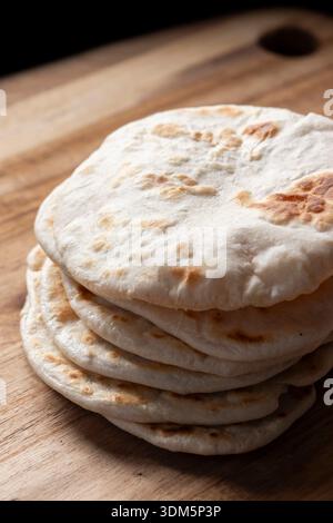 Hausgemachtes Fladenbrot auf einem hölzernen Schneidebrett. Einfaches Rezeptkonzept für hausgemachtes Brot. Stockfoto