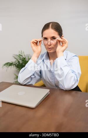 Geschäftsfrau professionelle Konzentration ernsthafte junge Frau, die Brillen am Schreibtisch mit Kopierraum anpasst Stockfoto