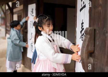 Südkorea. Februar 2026. Kinder und ein Kalligraf kleben am 4. Februar 2026 Ipchuncheop, traditionelle Kalligrafieblätter, die den Beginn des Frühlings begrüßen, an den Türen des Ochondack im National Folk Museum of Korea in Seoul, Südkorea. Ipchun ist der erste von 24 Sonnenterminen, der den Beginn der Frühlingssaison signalisiert. (Foto: Chris Jung/NurPhoto) Credit: NurPhoto SRL/Alamy Live News Stockfoto