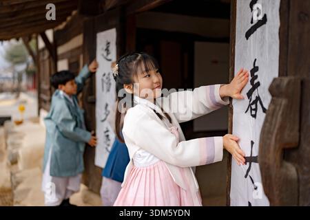 Südkorea. Februar 2026. Kinder und ein Kalligraf kleben am 4. Februar 2026 Ipchuncheop, traditionelle Kalligrafieblätter, die den Beginn des Frühlings begrüßen, an den Türen des Ochondack im National Folk Museum of Korea in Seoul, Südkorea. Ipchun ist der erste von 24 Sonnenterminen, der den Beginn der Frühlingssaison signalisiert. (Foto: Chris Jung/NurPhoto) Credit: NurPhoto SRL/Alamy Live News Stockfoto