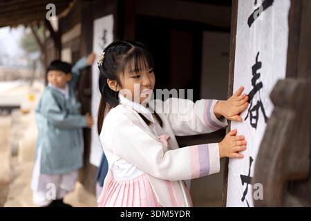 Südkorea. Februar 2026. Kinder und ein Kalligraf kleben am 4. Februar 2026 Ipchuncheop, traditionelle Kalligrafieblätter, die den Beginn des Frühlings begrüßen, an den Türen des Ochondack im National Folk Museum of Korea in Seoul, Südkorea. Ipchun ist der erste von 24 Sonnenterminen, der den Beginn der Frühlingssaison signalisiert. (Foto: Chris Jung/NurPhoto)0 Credit: NurPhoto SRL/Alamy Live News Stockfoto