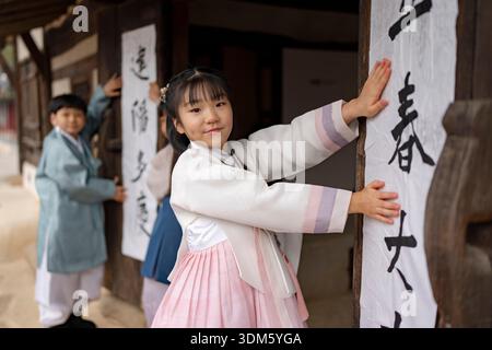 Südkorea. Februar 2026. Kinder und ein Kalligraf kleben am 4. Februar 2026 Ipchuncheop, traditionelle Kalligrafieblätter, die den Beginn des Frühlings begrüßen, an den Türen des Ochondack im National Folk Museum of Korea in Seoul, Südkorea. Ipchun ist der erste von 24 Sonnenterminen, der den Beginn der Frühlingssaison signalisiert. (Foto: Chris Jung/NurPhoto)0 Credit: NurPhoto SRL/Alamy Live News Stockfoto