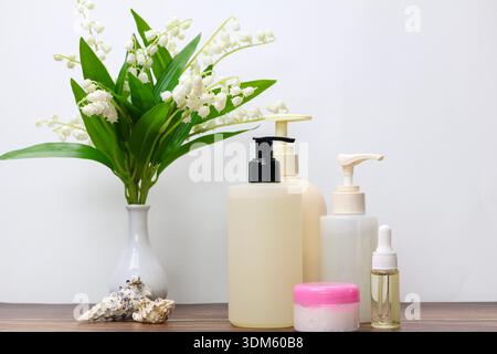 Natürliche Hautpflegeprodukte mit Maiglöckchen auf Holztisch Stockfoto