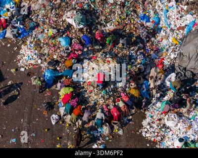 Chattogram, Bangladesch - 25. November 2025: Luftaufnahme einer weitläufigen Mülldeponie, wo Figuren in lebendiger Kleidung inmitten des schroffen weiß und V Stockfoto