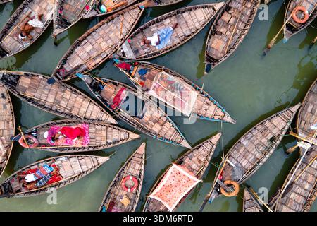 Dhaka, Bangladesch - 31. August 2024: Aus der Vogelperspektive auf Holzbooten, die eng aneinander gruppiert sind und ein Mosaik aus Texturen und Tönen auf dem Wasser bilden Stockfoto