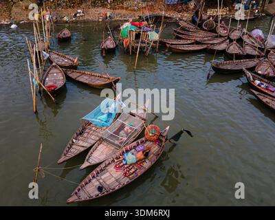 Dhaka, Bangladesch - 31. August 2024: Aus der Vogelperspektive einer Gruppe traditioneller Holzboote, die auf dem trüben Wasser in der Nähe eines Ufers schwimmen, eine lebendige Tablea Stockfoto