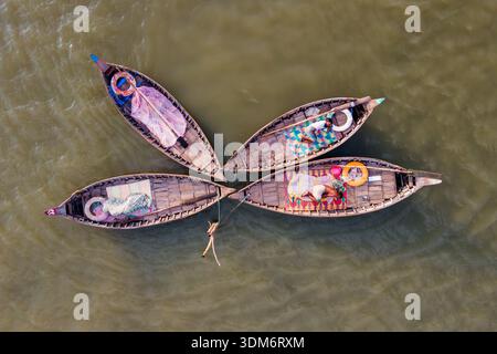 Dhaka, Bangladesch - 31. August 2024: Aus der Vogelperspektive von vier traditionellen Holzbooten, die in einem Blumenmuster angeordnet sind, deren farbenfrohe Inhalte sich mit einem Kontrast abheben Stockfoto