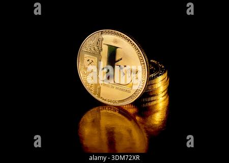 Litecoin-Münze isoliert auf schwarzem Hintergrund. Stapel Goldmünzen mit Litecoin-Münze davor. Goldene Litecoin-Münze. Kryptowährung. Stockfoto