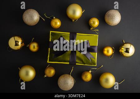 Foto von oben von Geschenkschachtel in goldener Verpackung mit schwarzer Satinschleife und Anhänger auf isoliertem schwarzem Hintergrund mit Copyspace Stockfoto