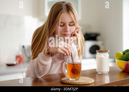 Teenager Rührt Zucker In Einer Tasse Tee Zu Hause Stockfoto