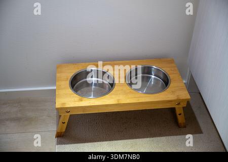 Erhöhte Hundefutter-Station mit zwei Edelstahlschalen auf Holzständer Stockfoto
