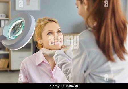 Kosmetikerin untersucht das Gesicht weiblicher Klientinnen vor oder nach Schönheitspflege Stockfoto