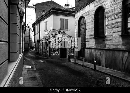 Atmosphärische monochrome Stadtfotografie mit einer großen Eule-Illustration und verschiedenen Figuren, die an einer Ecke eines antiken Gebäudes gemalt sind Stockfoto