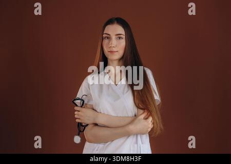 Stehend mit gekreuzten Armen. Die Ärztin ist im Studio. Stockfoto