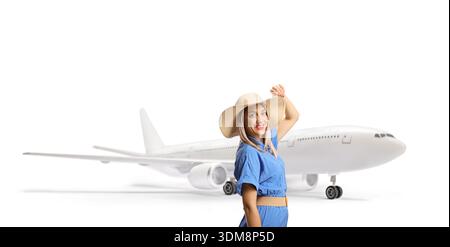 Frau in blauem Kleid und Strohhut, die auf ein Flugzeug auf weißem Hintergrund zugeht Stockfoto