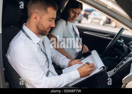 Seitenansicht. Frau ist mit Lehrer im Auto, Fahrschulkonzept. Stockfoto