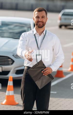 Fahrschularbeiter ist draußen in der Nähe des Autos. Stockfoto