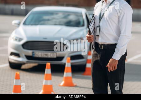 Notizblock liegt in der Hand. Fahrschularbeiter ist draußen in der Nähe des Autos. Stockfoto
