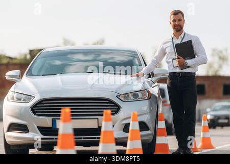 Sich auf das Auto zu lehnen. Fahrschularbeiter ist draußen. Stockfoto