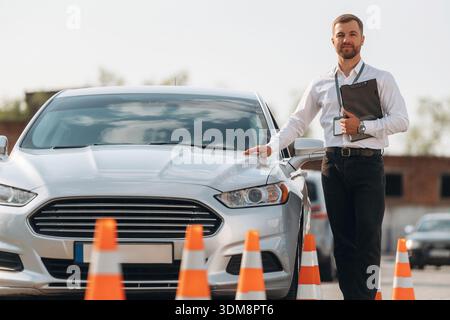Sich auf das Auto zu lehnen. Fahrschularbeiter ist draußen. Stockfoto