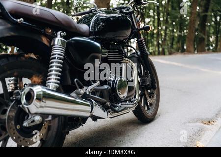 Detaillierte Nahaufnahme des schwarzen Motorrads, das auf der Straße geparkt ist. Stockfoto