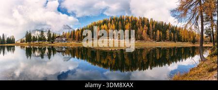 Panoramablick auf den Antorno-See, umgeben von Herbstlärchen, alpinen Bergen und stillen Wasserspiegeln unter bewölktem Himmel in den Dolomiten, Italien Stockfoto