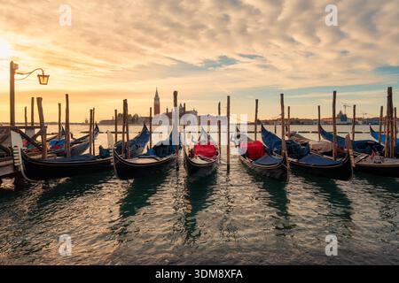 Wunderschöner Sonnenaufgang über traditionellen Gondeln entlang der Uferpromenade und San Giorgio Maggiore in Venedig, Italien Stockfoto