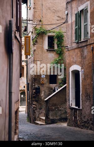 Eine sonnendurchflutete, enge Straße in Tivoli, Italien, mit verwitterten Gebäuden und Kletterei Stockfoto