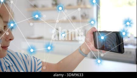 Ich halte ein Teenager-Mädchen, das Selfie mit Telefon in der Küche macht, mit gestreiftem Oberteil, Knotenüberzug, Kopierraum Stockfoto
