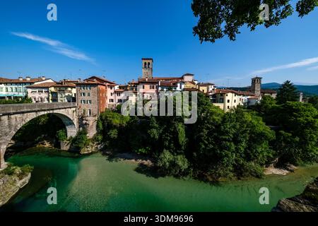 Die Steinbrücke Teufelsbrücke über den türkisfarbenen Fluss Natisone mit der Kirche San Francesco auf einer Klippe in Cividale del Friuli. Stockfoto