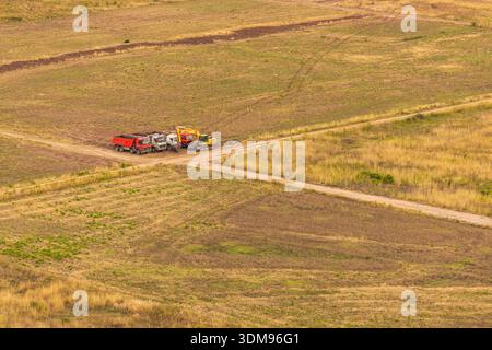 Ravno, Bosnien und Herzegowina - 19. August 2022: Erdbewegungsmaschinen parkten auf einem Feldweg auf einem Trockenfeld in Ravno, Bosnien und Herzegowina. Stockfoto