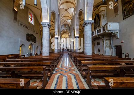 Das Innere der Kirche Duomo di Santa Maria Assunta mit seinem Kirchenschiff, Säulen, Holzbänken und dem Altar in der Ferne. Stockfoto