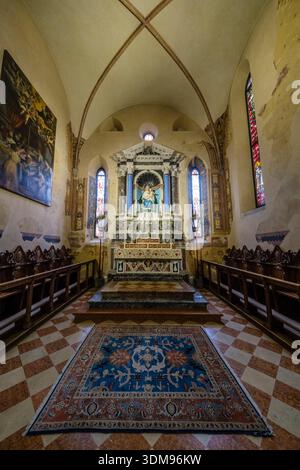 Blick auf den Hochaltar in der Kirche Duomo di Santa Maria Assunta mit Steintreppen, massiven Säulen und Buntglasfenstern in der Ferne. Stockfoto